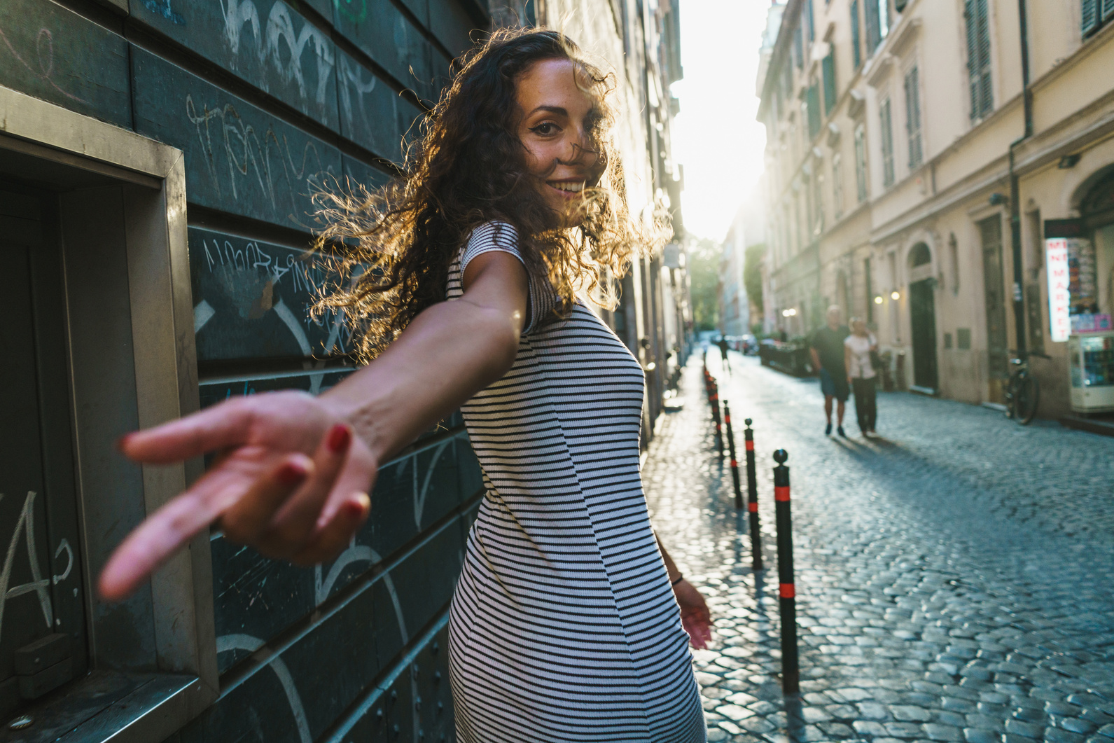 Hispanic Woman Reaching Hand Looking over Shoulder While Walking
